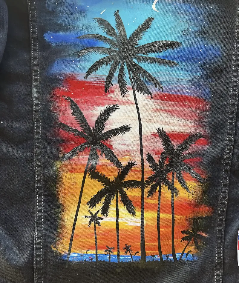 Rücken einer schwarzen Jeansjacke mit Palmen im Sonnenuntergang